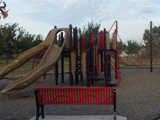 A playground with a bright slide and a bench